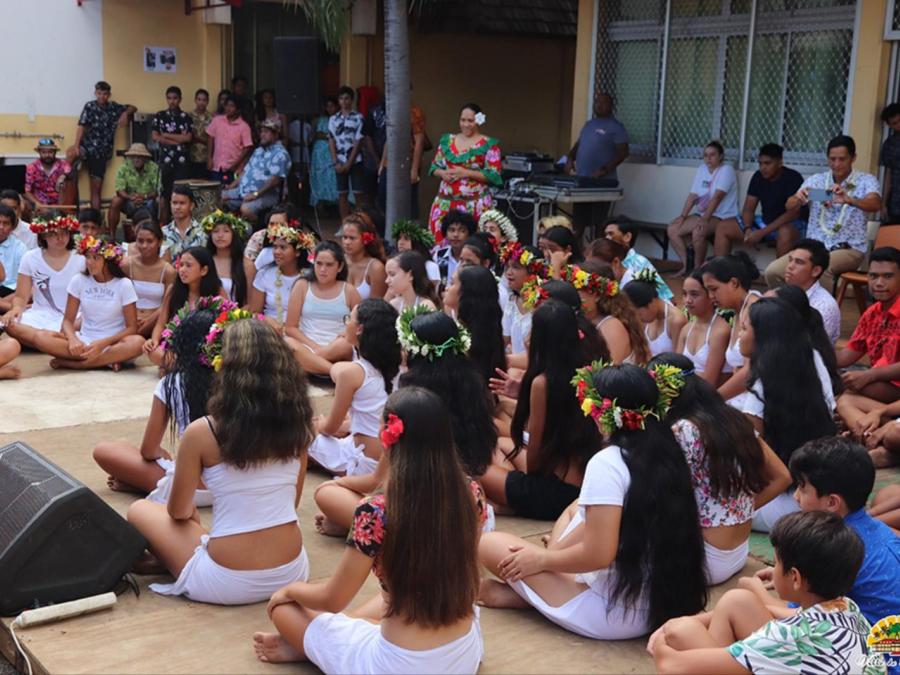 Élèves danseuses couronnées de fleurs, assises dans la cour avant leur passage