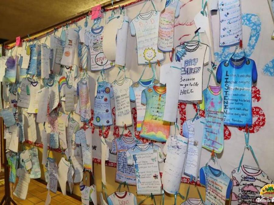 Mur de tee-shirts en papier dessinés par les élèves, avec des messages contre le harcèlement