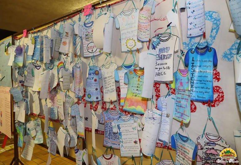 Mur de tee-shirts en papier dessinés par les élèves, avec des messages contre le harcèlement